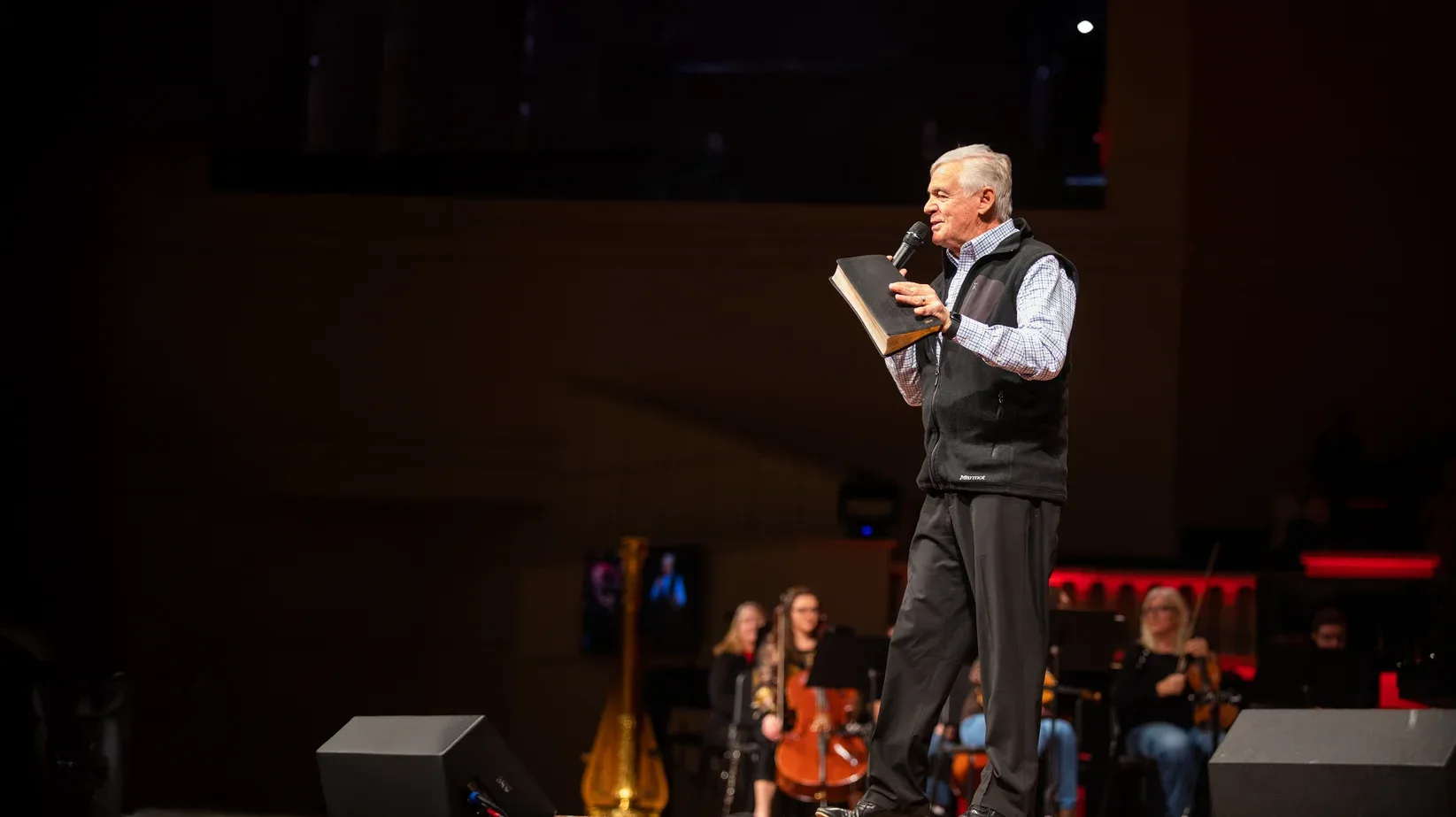 Pastor Ken Whitten preaching in front of the orchestra